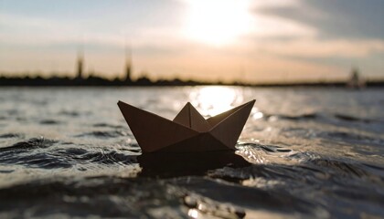 Paper boat sailing on water at sunset with city skyline.