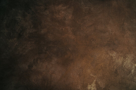 The texture of a brown, vintage plaster wall. The dark brown background use as backdrop in design