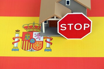 Residential house with stop sign on Spanish flag close up. Concept of Squatting in Spain. Okupas problem