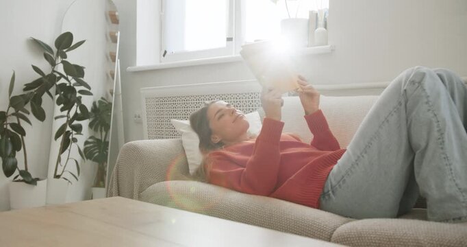 Young woman relaxing on the couch reading a book at home