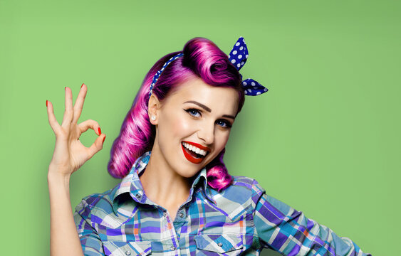Pin up cute girl. Portrait of expressive smile red purple hair pinup woman show ok okay zero cost hand sign gesture. Retro vintage ad concept. Isolated green color background.