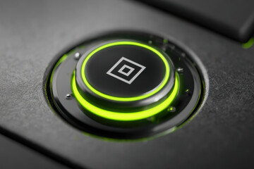Illuminated gaming controller button with green led ring and geometric icon on matte black surface in a modern tech setup