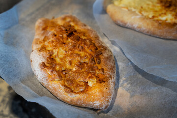 Freshly baked flatbread topped with cheese and onions on parchment paper in a rustic kitchen