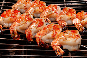 Grilled shrimp skewers cooking on a barbecue grill with smoke rising in a backyard setting during summer evening