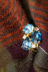 Close-up of a blue gemstone ring set against textured woven fabric.