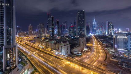 Fototapeta premium Aerial view on downtown and financial district in Dubai during all night timelapse, United Arab Emirates with skyscrapers and highways.