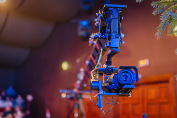 Professional camera mounted on a crane, capturing dynamic shots in a studio setting, illuminated by colorful lights, showcasing advanced filming technology and creative production