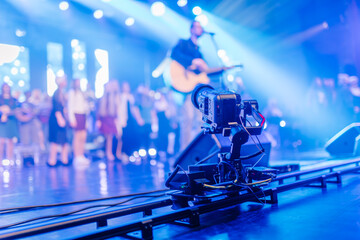 Camera on a dolly track captures a live music performance with vibrant stage lights and blurred audience, showcasing the excitement of a concert atmosphere and dynamic visual storytelling