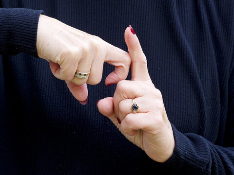 A pair of hands signing the consonant letter 'K' in British Sign Language.BSL.Communication.Hearing Impaired.