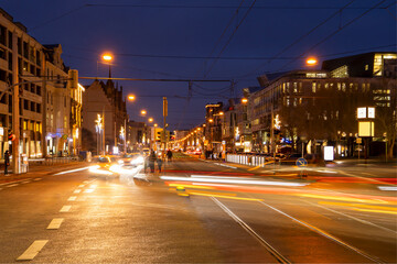 city traffic scene in twilight, long exposure with light trails and motion blur of cars and people, christmas light decoration in downtown district Magdeburg, Germany