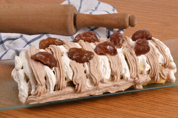 B&ucirc;che de No&euml;l poire et chocolat faite maison dans un plat en gros plan avec un rouleau &agrave; p&acirc;tisserie et un torchon au second plan