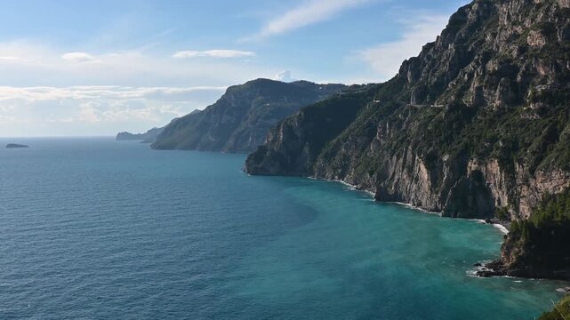 Panoramic view of the entire Amalfi Coast from Positano to Punta Campanella, with Capri island visible in the distance along the Mediterranean Sea, Italy.