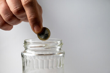 Putting Coin Into Glass Jar