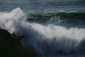 Fototapeta premium Crashing sea waves slam against rugged cliffs in a dramatic ocean seascape