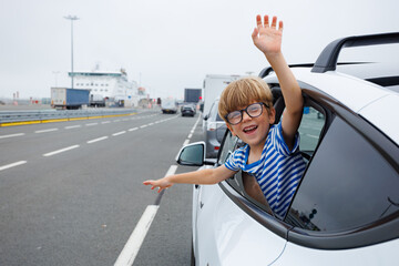 Happy boy enjoy car road trip wait for a ferry to cross channel