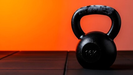Black 16kg Kettlebell Exercise Weight for Fitness Training and Gym Workout Set Against Vibrant Orange Background