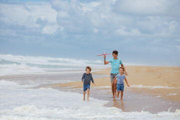 Kids enjoy beach fun run with a toy plane and the ocean waves