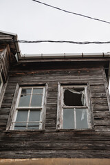 Abandoned wooden facade of the weathered house with broken window