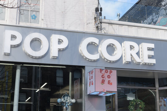 exterior building facade and sign of Popcore, a toy store, located at 322 1/2 Queen St W, Toronto