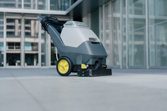 The worker is using a floor scrubber to clean the floor.
