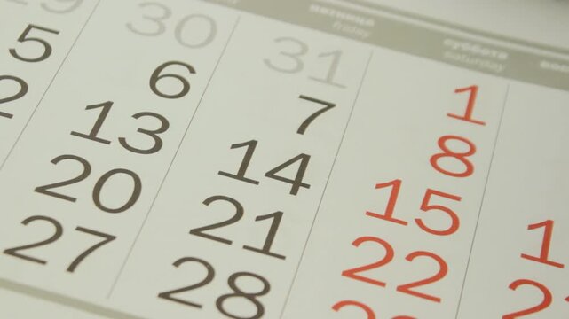 Close up of paper calendar sheets flipping quickly representing the flying years, changing months, urgent deadlines, and the rapid progression of business schedules and life events