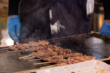 屋台の鉄板で焼かれる串焼きの肉