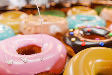 トレイに並んだカラフルなドーナツに白い液体クリームを垂らす
