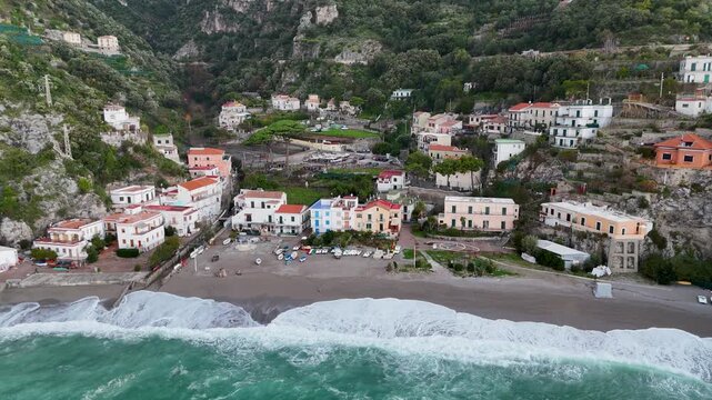 Aerial view of the vibrant Erchie beach with its historic coastal tower, set against the turquoise sea and rocky cliffs, Erchie, Amalfi Coast, Italy.