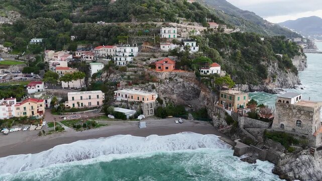 Aerial view of the vibrant Erchie beach with its historic coastal tower, set against the turquoise sea and rocky cliffs, Erchie, Amalfi Coast, Italy.