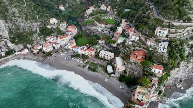 Aerial view of the vibrant Erchie beach with its historic coastal tower, set against the turquoise sea and rocky cliffs, Erchie, Amalfi Coast, Italy.