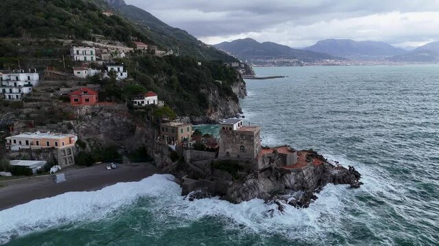 Aerial view of the vibrant Erchie beach with its historic coastal tower, set against the turquoise sea and rocky cliffs, Erchie, Amalfi Coast, Italy.