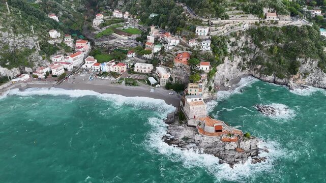 Aerial view of the vibrant Erchie beach with its historic coastal tower, set against the turquoise sea and rocky cliffs, Erchie, Amalfi Coast, Italy.
