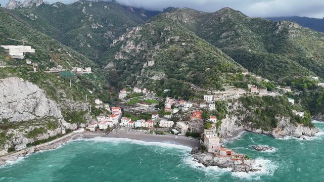 Aerial view of the vibrant Erchie beach with its historic coastal tower, set against the turquoise sea and rocky cliffs, Erchie, Amalfi Coast, Italy.