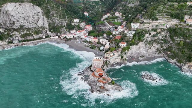 Aerial view of the vibrant Erchie beach with its historic coastal tower, set against the turquoise sea and rocky cliffs, Erchie, Amalfi Coast, Italy.