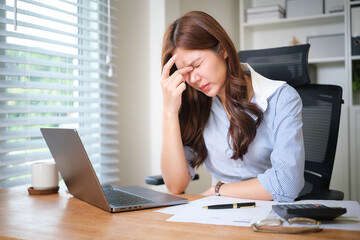 Obraz premium Young businesswoman feeling stressed while working on laptop in office.