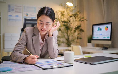Smiling businesswoman taking notes at her desk in a cozy, modern office.