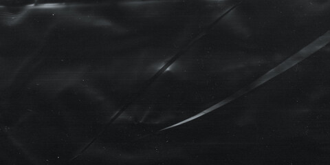 Wrinkled plastic wrap texture on a black background. Cellophane package wallpaper