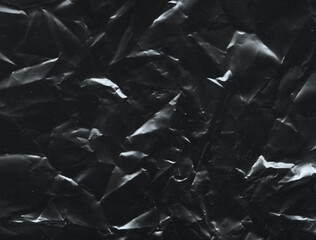 Wrinkled plastic wrap texture on a black background. Cellophane package wallpaper