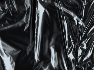 Wrinkled plastic wrap texture on a black background. Cellophane package wallpaper