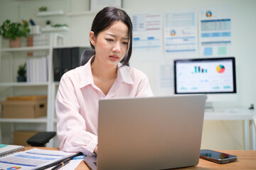 Concerned businesswoman looking at her laptop screen while analyzing financial reports at the office.