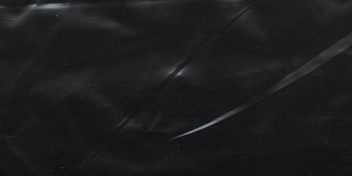 Wrinkled plastic wrap texture on a black background. Cellophane package wallpaper