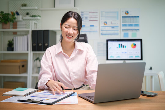 Smiling businesswoman working on reports and data analysis at her desk.