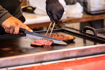 屋台の鉄板で焼いたジューシーな肉をナイフで切り分けるライブクッキング