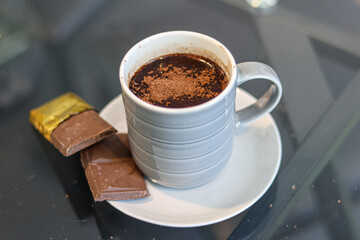 A serving of hot chocolate drink accompanied by a chocolate bar.