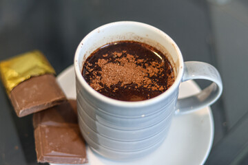 A serving of hot chocolate drink accompanied by a chocolate bar.