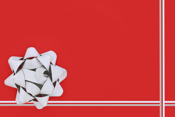 Silver glitter ribbon gift bow for present, greeting card, gift tag, label. Decorative contrast minimal art abstract design on red background.