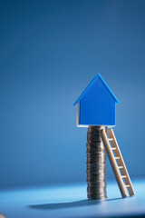 Step ladder and house model on top of stack of coins