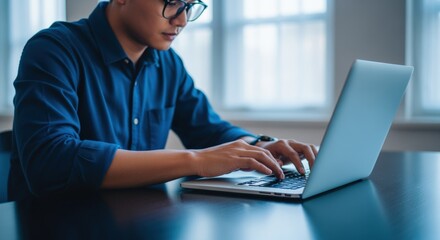 Focused young professional working on laptop in office setting, showcasing productivity and technology