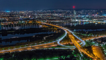 Aerial panoramic view over Vienna city with skyscrapers, historic buildings and a riverside promenade day to night timelapse in Austria.
