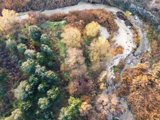 Colorful trees line a winding river in a natural landscape during autumn in a rural area